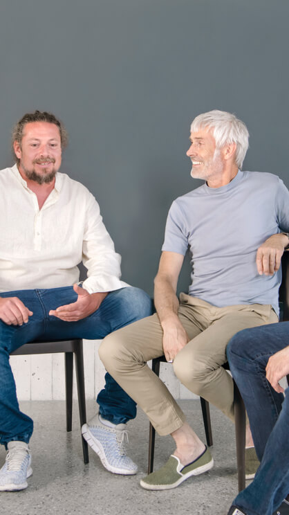 Vier Maenner sitzen in einer Runde und unterhalten sich